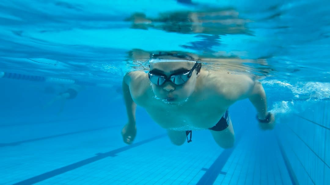 Swimmer wearing swimming goggles underwater in a pool