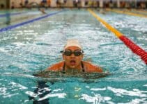 Competitive swimmer wearing a swim cap and goggles in an indoor pool