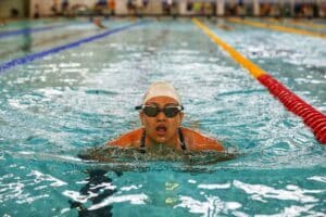 Competitive swimmer wearing a swim cap and goggles in an indoor pool